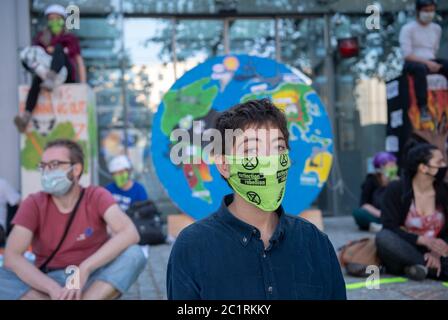 Berlin, Deutschland. Juni 2020. Aktivisten der Umweltschutzbewegung Extinction Rebellion (XR) sitzen bei einer Protestaktion vor dem Haus des Bundesverbandes der Deutschen Industrie (BDI), während eine Frau einen Mund- und Nasenschutz mit dem Logo Extinction Rebellion trägt. Quelle: Paul Zinken/dpa/Alamy Live News Stockfoto