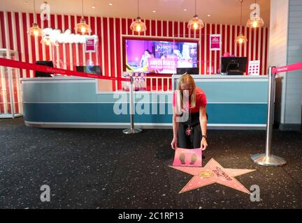 Ein Mitarbeiter des Hollywood Bowl in Thurrock, Essex, bereitet die sozialen Distanzierungszeichen vor. Eine von mehreren möglichen Maßnahmen zur Arbeitssicherheit, die in Erwartung zukünftiger Leitlinien der britischen Regierung zur Wiedereröffnung von Freizeitunternehmen ergriffen werden. Stockfoto