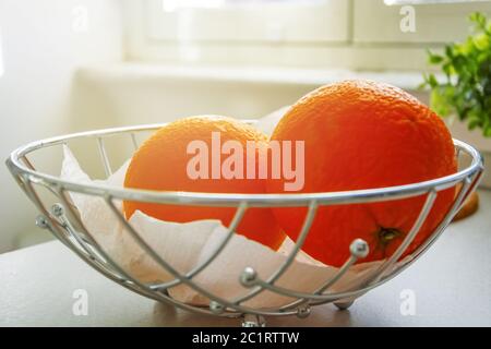 Ein paar Orangen in einem Metallkorb. Stockfoto