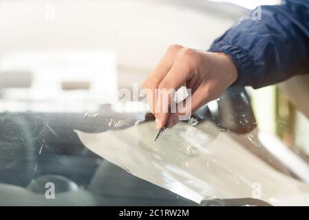 Nahaufnahme Auto Glasierer Arbeiter Befestigung und Reparatur Windschutzscheibe oder Windschutzscheibe eines Autos in Auto-Service-Station Garage Stockfoto