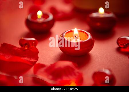 Romantische Dekoration für das Abendessen. Rote Kerzen, Blütenblätter, auf dem Tisch Stockfoto