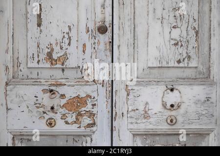 Detail einer alten verfallenen Tür mit weißem, rissigem Farbhintergrund Stockfoto