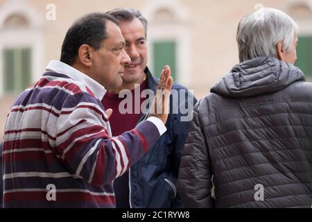 Drei italienische Männer sprechen und gestuurd miteinander auf dem Platz Piazza del Popolo in Ascoli Piceno, Italien Stockfoto