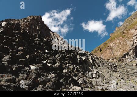 Weitwinkelansicht eines felsigen Abhangs an einem sonnigen Sommertag. Strukturelle sechseckige Klippen im Nordkaukasus Stockfoto