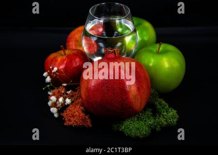 Foto Glas Wasser rot und grün Äpfel Moos in verschiedenen Farben auf schwarzem Hintergrund Stockfoto