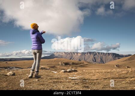 Portrait von der Rückseite eines Mädchen Reisenden in einer Jacke mit einer Kappe und einem Rucksack steht auf dem Hintergrund einer epischen Landschaft wi Stockfoto