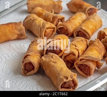 Nahaufnahme eines Tellers gekochter chinesischer/thailändischer Frühlingsrollen. Die goldenen und knusprigen Brötchen trocknen auf einem verzehrfertigen Teller. Stockfoto