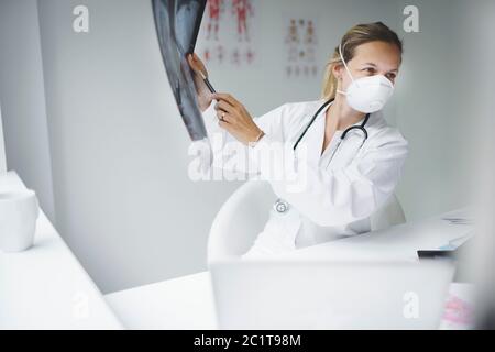 Wunderschöne junge Ärztin mit Mund und Nasenschutz Maske Stockfoto