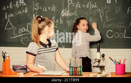 Bildungsexperiment. Mädchen Klassenkameraden studieren Chemie. Mikroskopteströhrchen chemische Reaktionen. Schüler im Chemieunterricht am Schwarzen Brett. Laborpraxis. Chemieklassen. Faszinierende Wissenschaft. Stockfoto