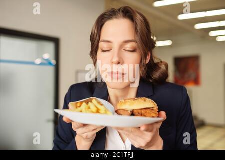 Zufriedene Gesicht Mädchen mit geschlossenen Augen mit Teller von Fast Food. Stockfoto