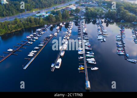 Luftaufnahme der Stadtpier mit vielen kleinen Booten im blauen Wasser mit Reflexion und Perspektive. Tilt Shift Shot. Stockfoto