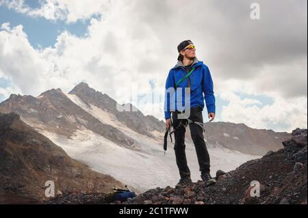 Portrait eines professionellen Bergführers eines Bergsteigers in einer Mütze und Sonnenbrille mit einer Eispickel in der Hand vor dem Hintergrund von t Stockfoto