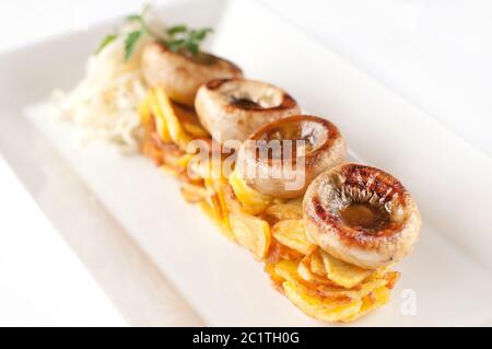 Bratkartoffeln mit Pilzen auf einem weißen Teller Stockfoto