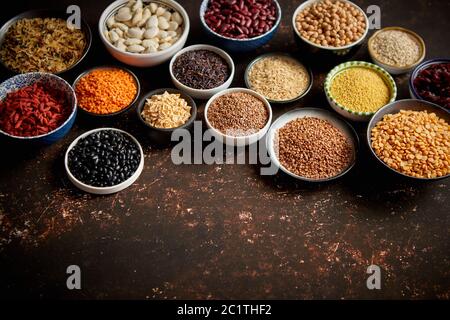 Verschiedene superfoods in kleinen Schüsseln auf dunklen Rusty Hintergrund Stockfoto