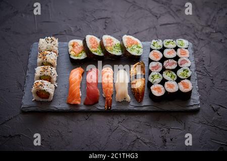 Sushi Brötchen mit Lachs und Thunfisch set serviert auf schwarzen Stein board Stockfoto