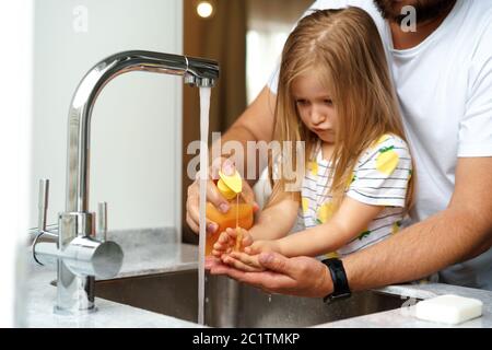 Vater und Tochter waschen sich die Hände über dem Waschbecken in einer Küche Stockfoto