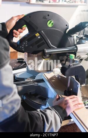 Nahaufnahme der Hände nach dem Beruf ein Zimmermann schneidet Holzbretter mit einer Kreissäge auf einem Arbeitstisch in einer Werkstatt. Professio Stockfoto