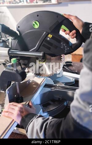 Nahaufnahme der Hände nach dem Beruf ein Zimmermann schneidet Holzbretter mit einer Kreissäge auf einem Arbeitstisch in einer Werkstatt. Professio Stockfoto