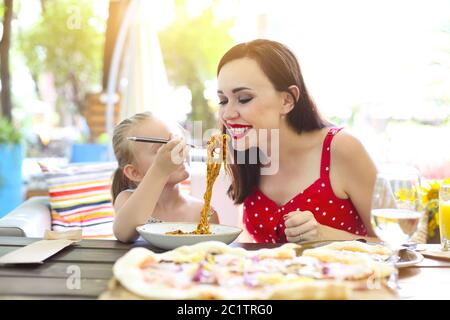 Glückliche Mutter und Tochter essen Spaghetti Bolognese im Restaurant Stockfoto