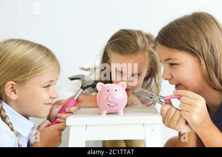 Kinder mit Schraubendreher, Zange und Hammer durch die rosa Schweinebank Stockfoto