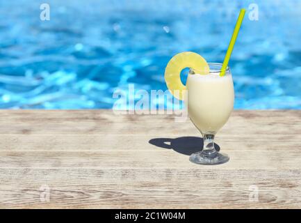 Ein Glas Pinacolada Cocktail steht auf der Kante des Swimmingpools Stockfoto