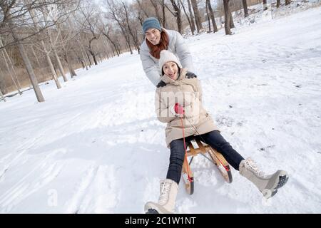 Das junge Paar Rodeln im Schnee Stockfoto