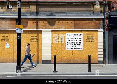 Frau, die an einem aufgekalten Laden in Doncaster, South Yorkshire, England, vorbeigeht Stockfoto