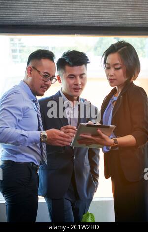 Gruppe von drei asiatischen Geschäftsleuten, die gemeinsam an einem neuen Geschäftsstrategieplan arbeiten, vertikal mittel lang Stockfoto