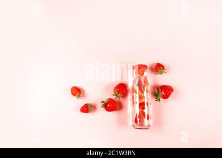 Draufsicht Zusammensetzung der hausgemachten Detox Limonade mit Bio-köstlichen Erdbeerbeeren in einer Glasflasche auf pnk Hintergrund. Sommer Komposition, minimalistischer Stil Stockfoto