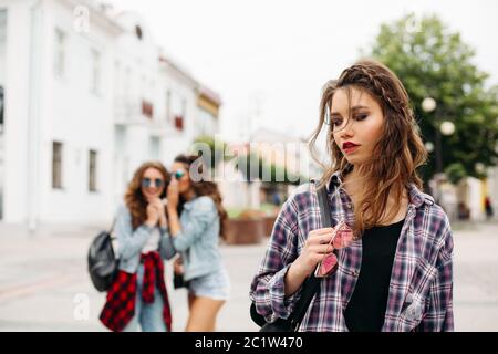 Eifersüchtig Mädchen Flüstern über dritte Mädchen vor der Kamera. Stockfoto