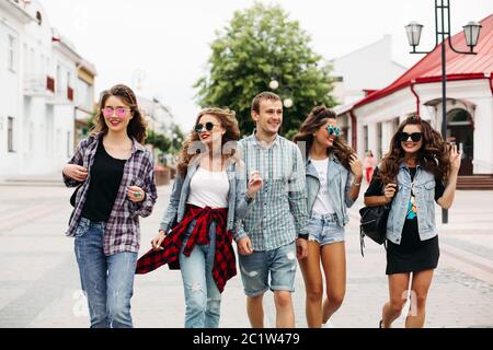 Tredny lächelnd Freundinnen zu Fuß entlang der Straße mit der einzige Mann. Stockfoto