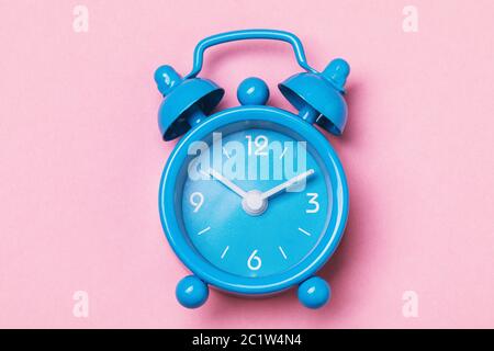 Blauer Wecker auf rosa Hintergrund, Draufsicht Stockfoto