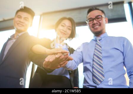 Gruppe von drei asiatischen Geschäftsleute verbinden ihre Hände machen Einheit Geste symbolisieren Teamarbeit, horizontale Low-Angle-Aufnahme Stockfoto