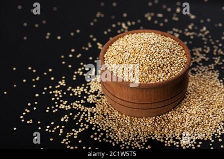 Quinoa-Samen. Schale mit gesunden weißen Quinoa-Körnern auf schwarzem Hintergrund, Nahaufnahme Stockfoto