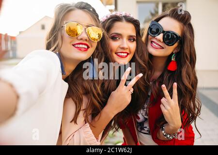 Schöne Freundinnen in Sonnenbrillen übersicht Frieden Zeichen an der Kamera mit Lächeln. Stockfoto