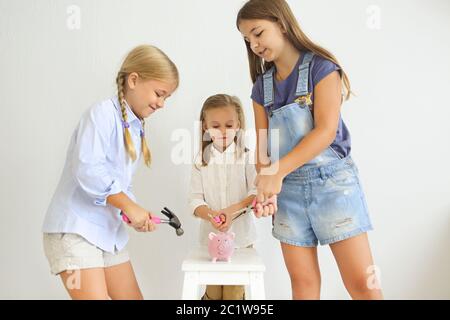 Kinder mit Schraubendreher, Zange und Hammer durch die rosa Schweinebank Stockfoto