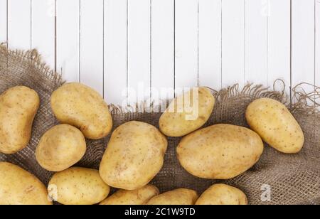 Rohe Kartoffel, Haufen von Kartoffeln auf sackleinen auf weissem Holztisch Stockfoto