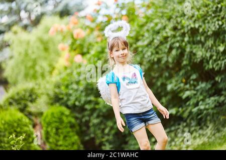 Gutes Kind als Engel mit Heiligenschein an einem Karneval im Garten Stockfoto