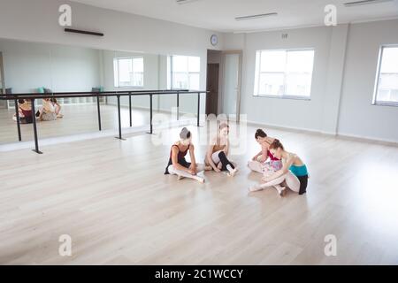 Kaukasische weibliche Balletttänzerinnen, die in einem hellen Ballettstudio ein Gespräch führen und glücklich aussehen Stockfoto