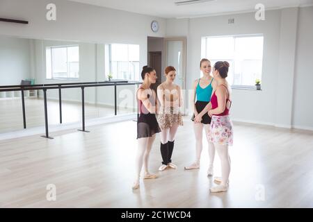 Kaukasische weibliche Balletttänzerinnen, die in einem hellen Ballettstudio ein Gespräch führen und glücklich aussehen Stockfoto