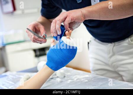 Arzt verband Gips an Kinder zerbrochenen Handknochen im Krankenhaus Stockfoto