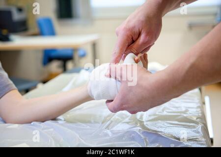 Arzt verband Gips an Kinder zerbrochenen Handknochen im Krankenhaus Stockfoto