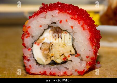 Sushi Roll mit geräuchertem Aal, Tomate, Frischkäse und masago Caviar auf Holzbrett Stockfoto