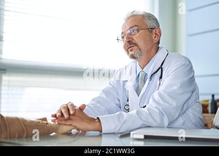 Arzt und Patient sind etwas, nur Hände am Tisch diskutieren. Stockfoto