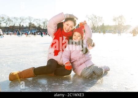 Junge Mütter und Kinder spielen auf der Eisbahn Stockfoto