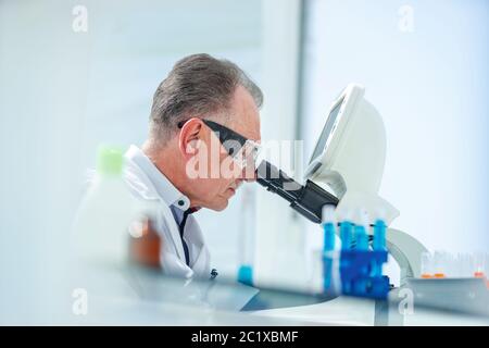 Nahaufnahme. Wissenschaftler, der sorgfältig durch ein Mikroskop schaut. Stockfoto