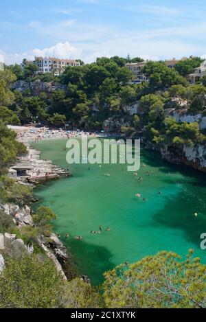 Touristen Baden in der Bucht von Cala Pi in der Nähe von alten Bootshäusern, Mallorca Südküste, August. Stockfoto