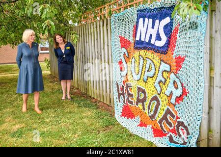 Die Herzogin von Cornwall wird von der Chief Executive Officer, Gloucestershire Hospitals NHS Foundation, Deborah Lee, als sie bei einem Besuch im Gloucestershire Royal Hospital mit Schlüsselarbeitern zusammentreffen, die auf die COVID-19-Pandemie reagiert haben, eine gestrickte Hommage an die Mitarbeiter des NHS gezeigt. Stockfoto