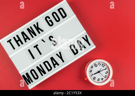 Text GOTT SEI DANK IST ES MONTAG TAG auf Leuchtkasten auf rotem Hintergrund mit Wecker. Stockfoto