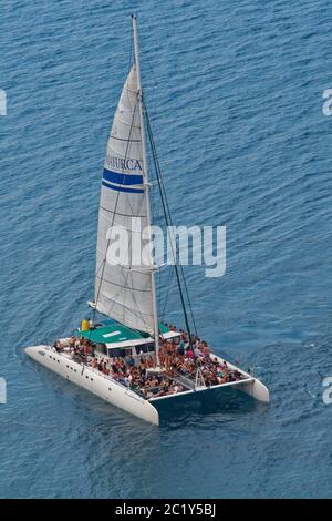 Katamaran voller junger Leute auf einer Party-Bootstour entlang der Küste der Llevant Halbinsel, nahe Port d’Alcudia, Mallorca Nordostküste, August. Stockfoto